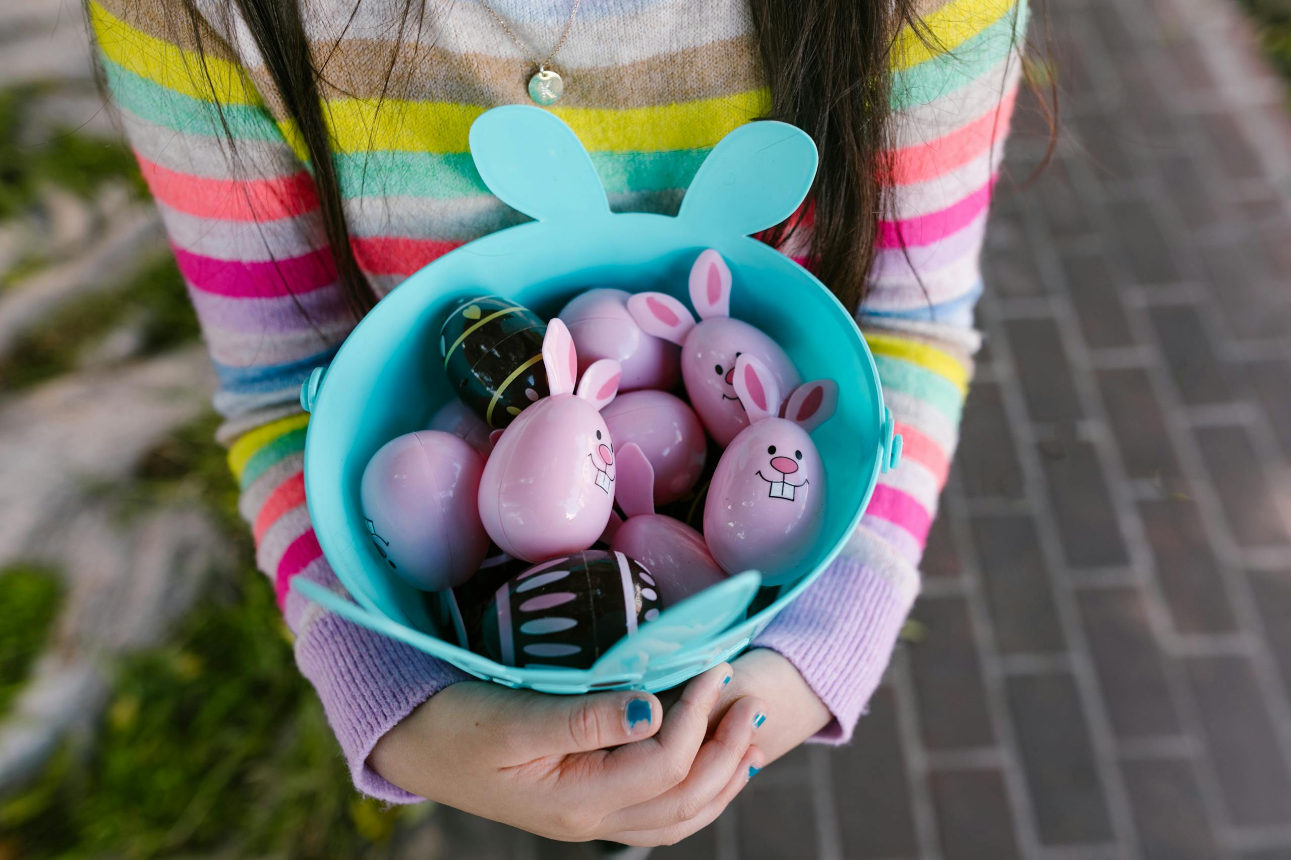 A child holds a colorful basket filled with Easter eggs during springtime.