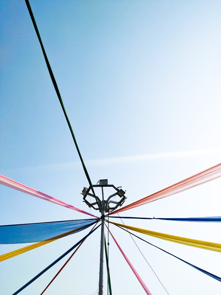 Vibrant multicolored ribbons on a maypole set against a clear blue sky during a spring festival.