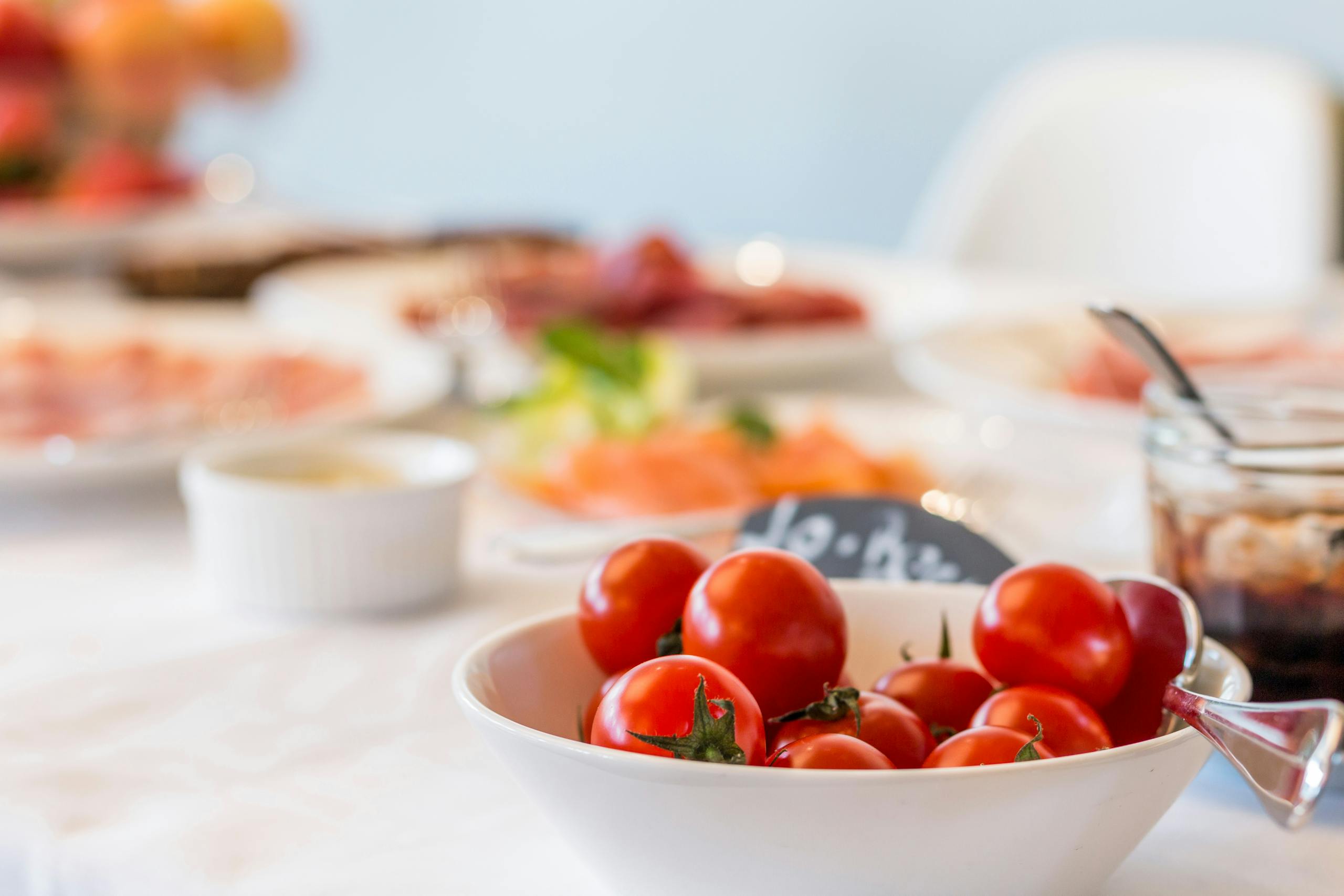 Close-up shot of vibrant cherry tomatoes in a bowl on a well-set dining table.